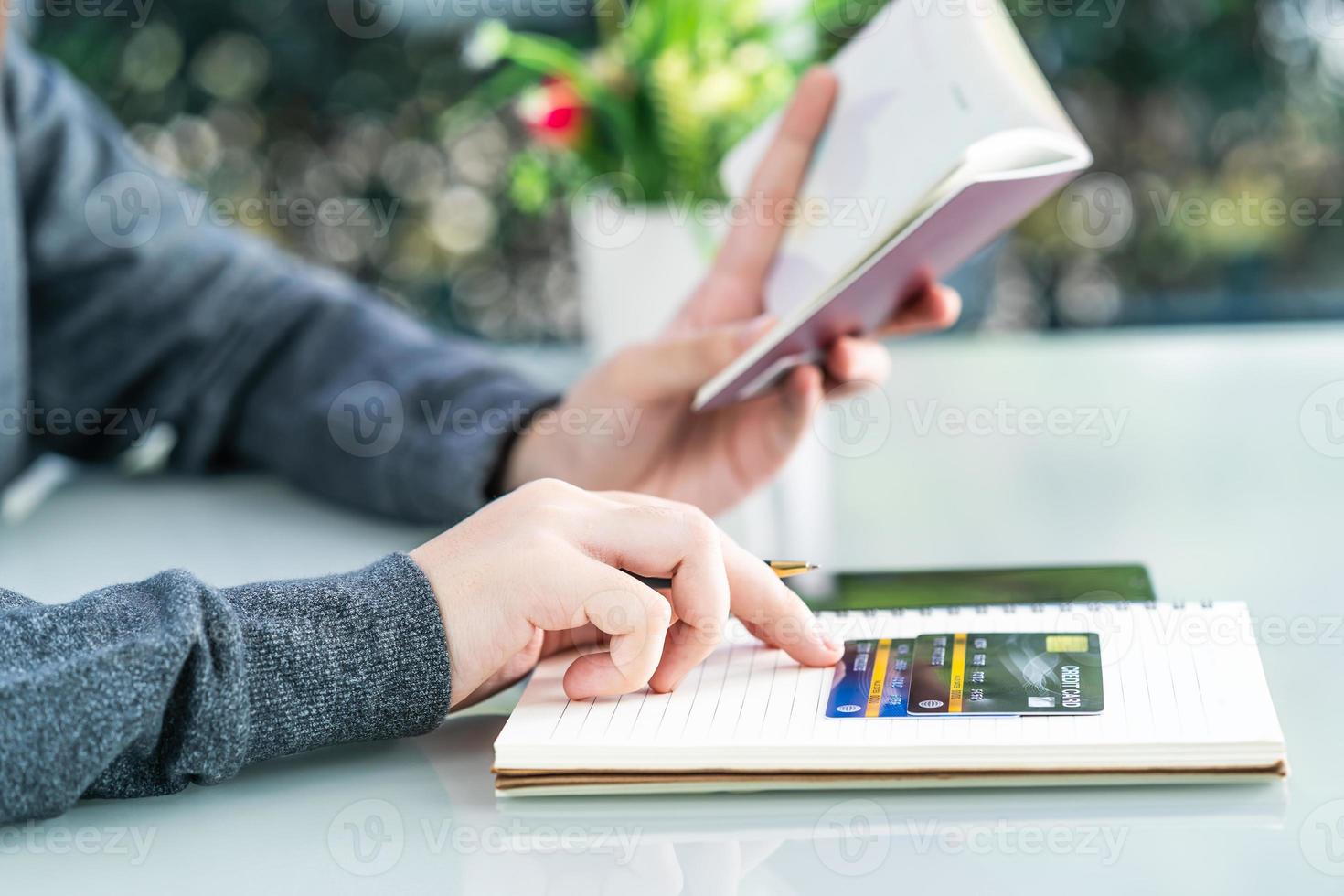 Woman writing on notebook with credit card and smartphone  desk photo