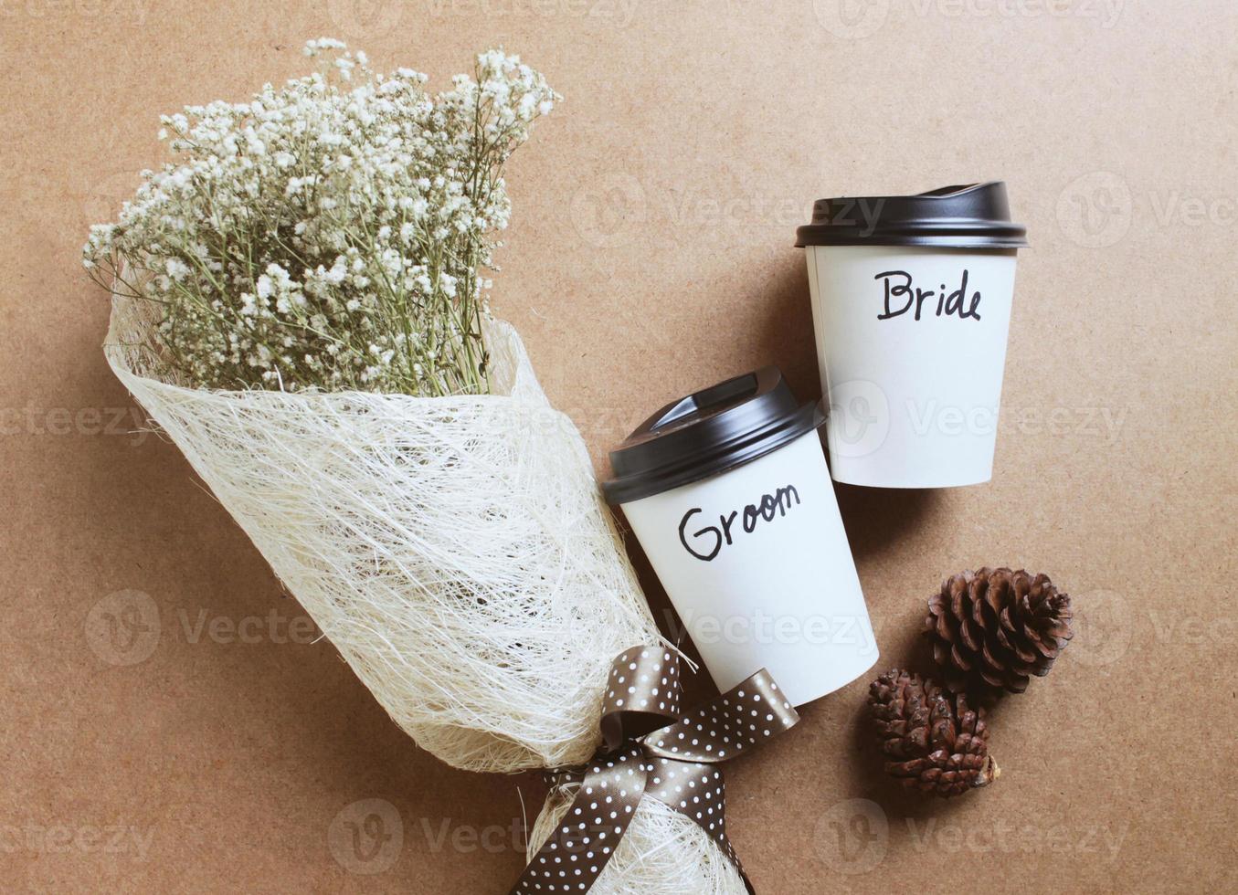 novio y novia escritos en una taza de café con ramo de flores para el concepto de boda foto