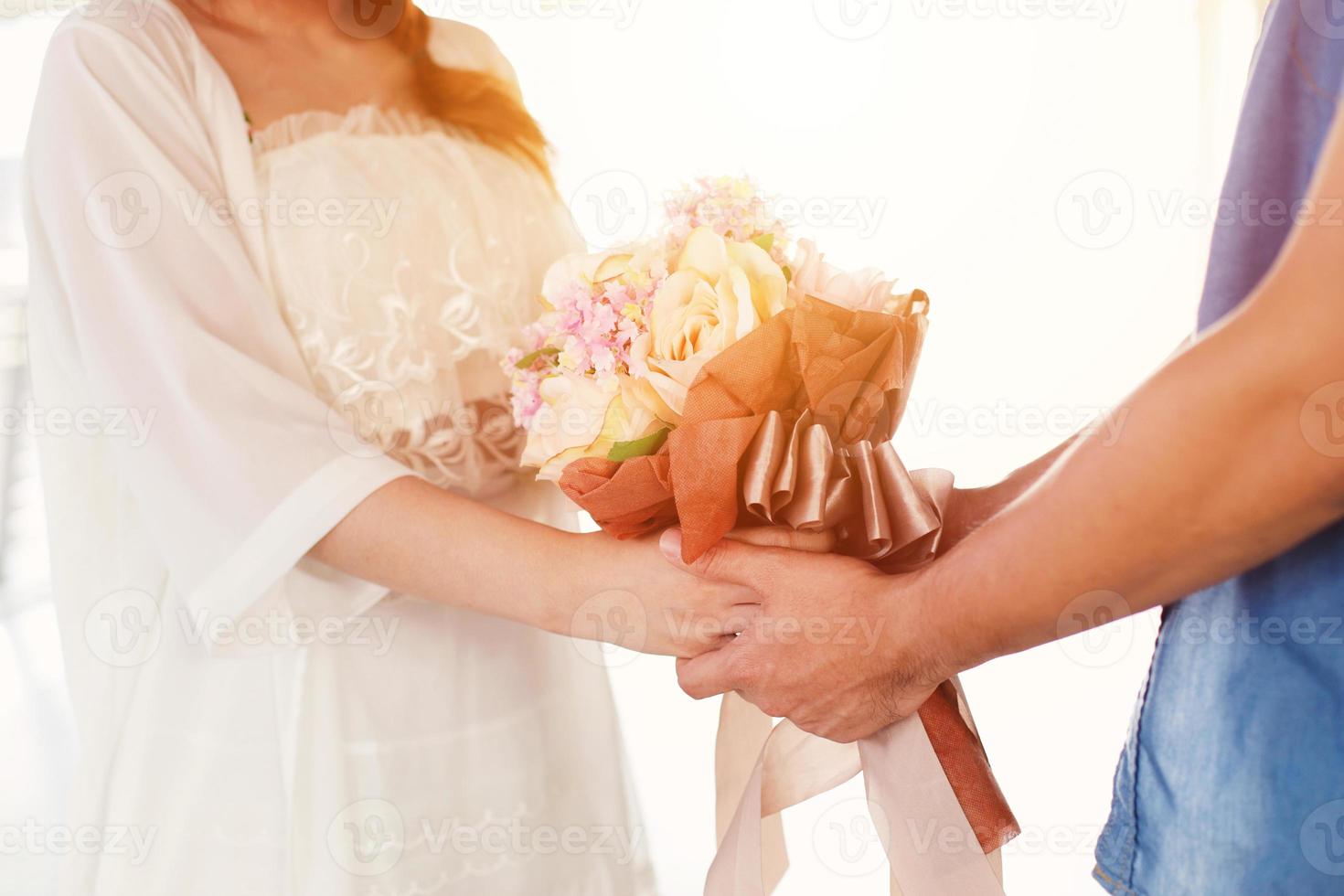 Midsection of couple holding hands and beautiful bouquet of flowers on white background, valentine day concept photo