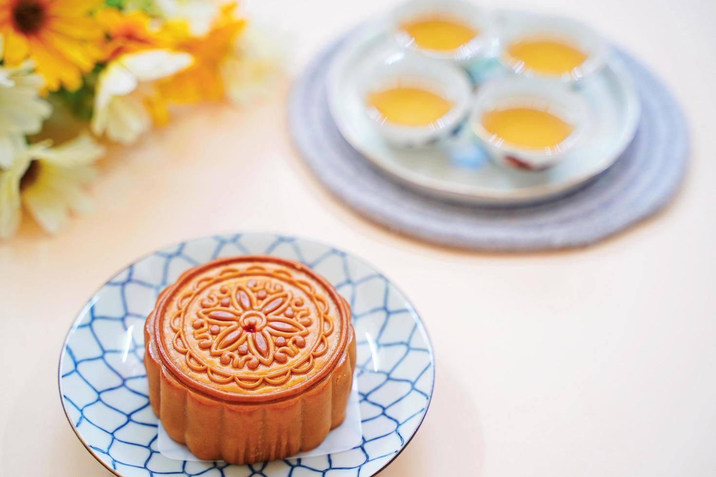 Top view of chinese moon cake with hot tea and flower on yellow background, holiday and festival concept photo