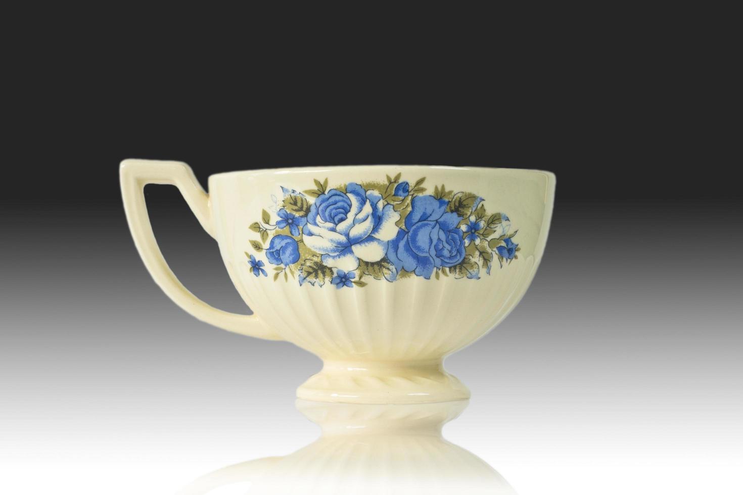 Flowered antique tea cup isolated on a reflection background. photo