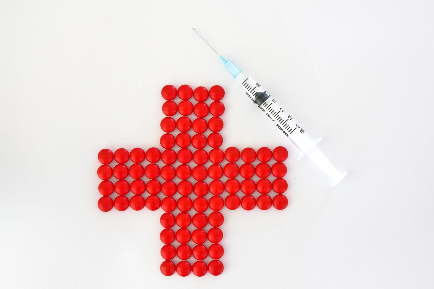 red cross made with red pills and  syringe photo