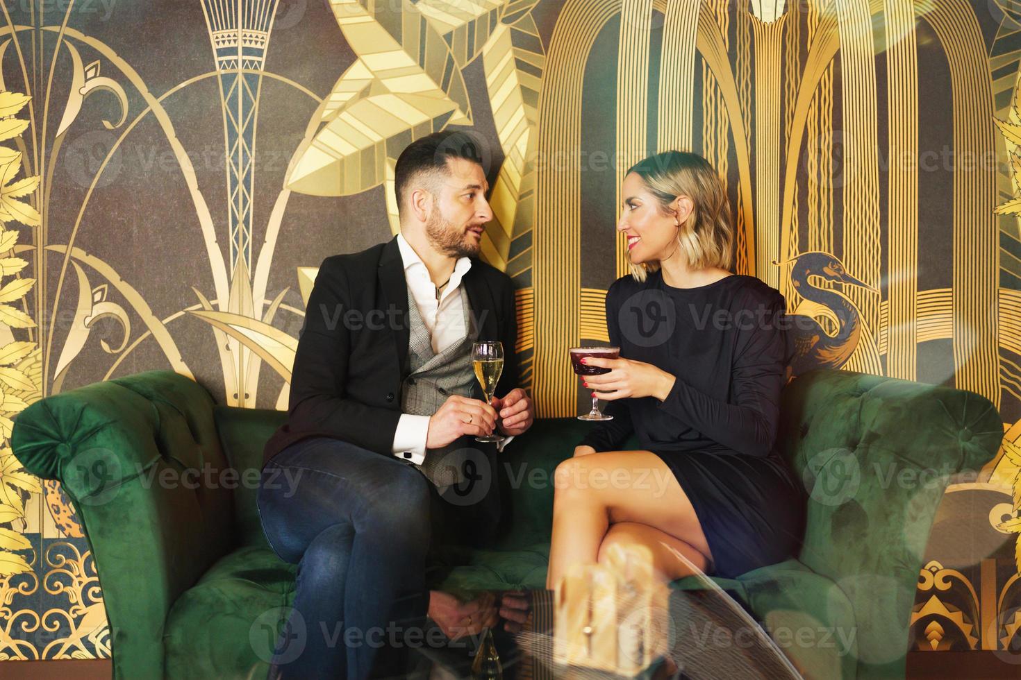Loving middle aged couple on couch with drinks on coffee table in hotel lobby photo
