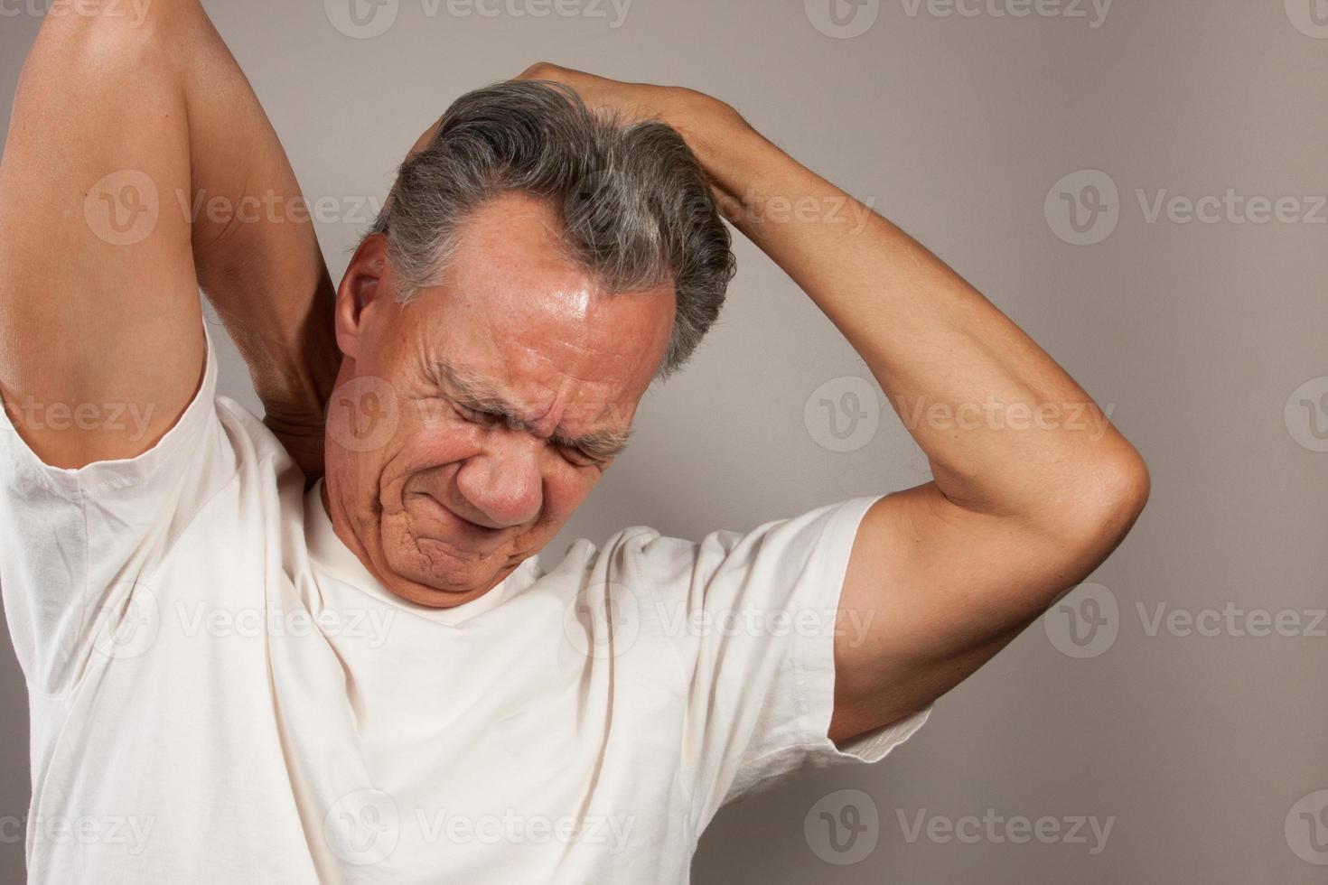 Mature Man 60plus doing back of the neck stretches for back and neck pain photo