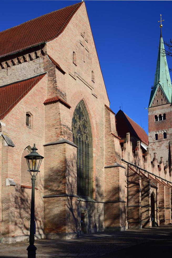 In december 2020, the cathedral in Augsburg stands behind bare trees and against a blue sky photo