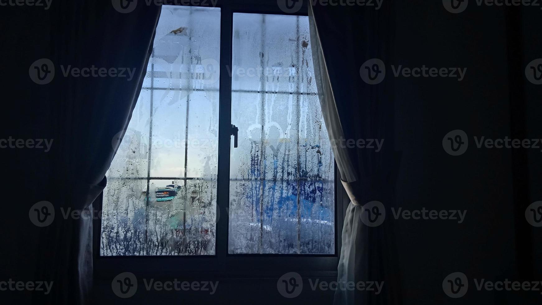 vista desde la ventana en la mañana fría con gotas de lluvia de agua sobre el vidrio foto