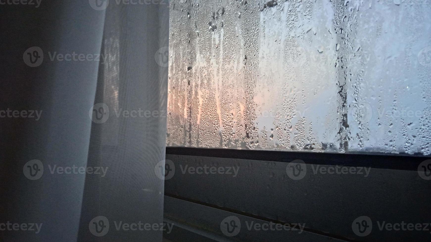 vista desde la ventana en la mañana fría con gotas de lluvia de agua sobre el vidrio foto