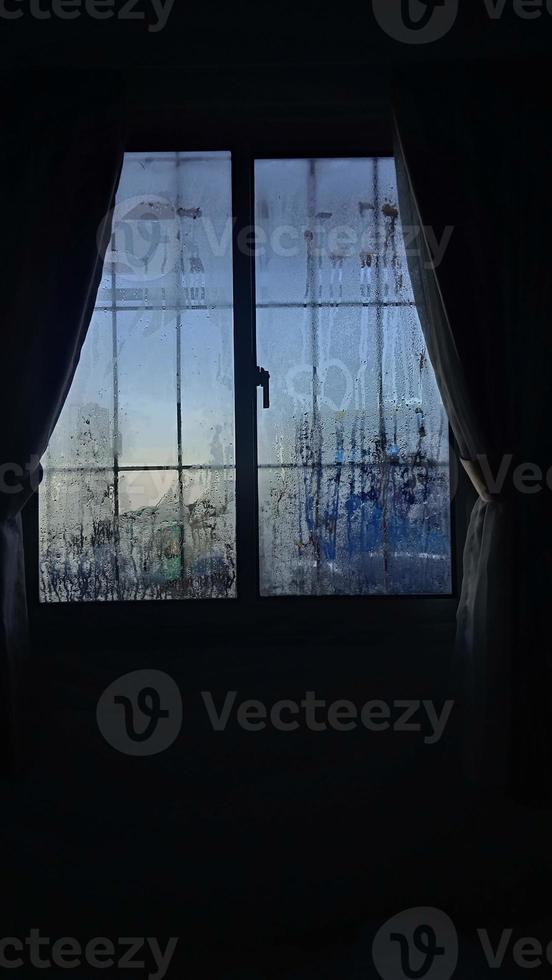 vista desde la ventana en la mañana fría con gotas de lluvia de agua sobre el vidrio foto