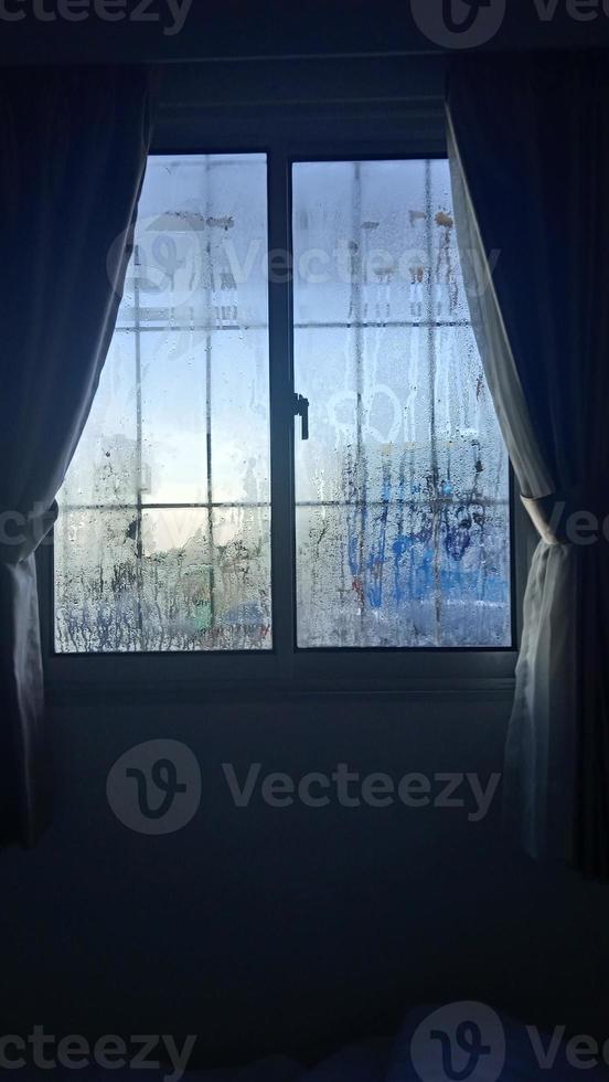 vista desde la ventana en la mañana fría con gotas de lluvia de agua sobre el vidrio foto