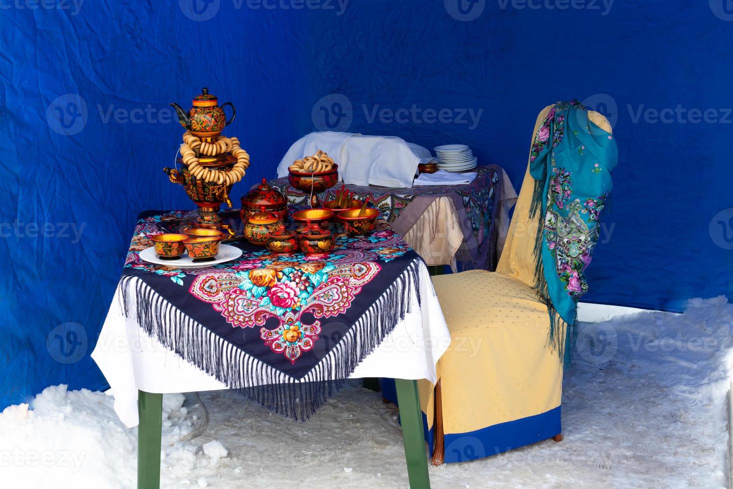 On the table on a colorful tablecloth is a traditional Russian samovar. Russian national tea ceremony photo