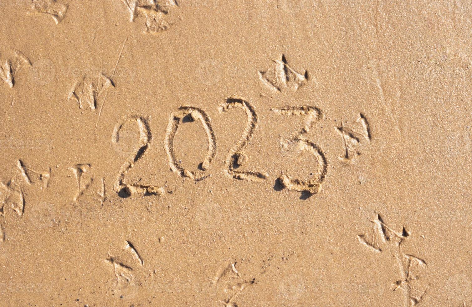 The numbers 2023 are written on the sand on the beach. The concept of the New Year. Happy New Year 2023 background. Travel during the Christmas holidays photo