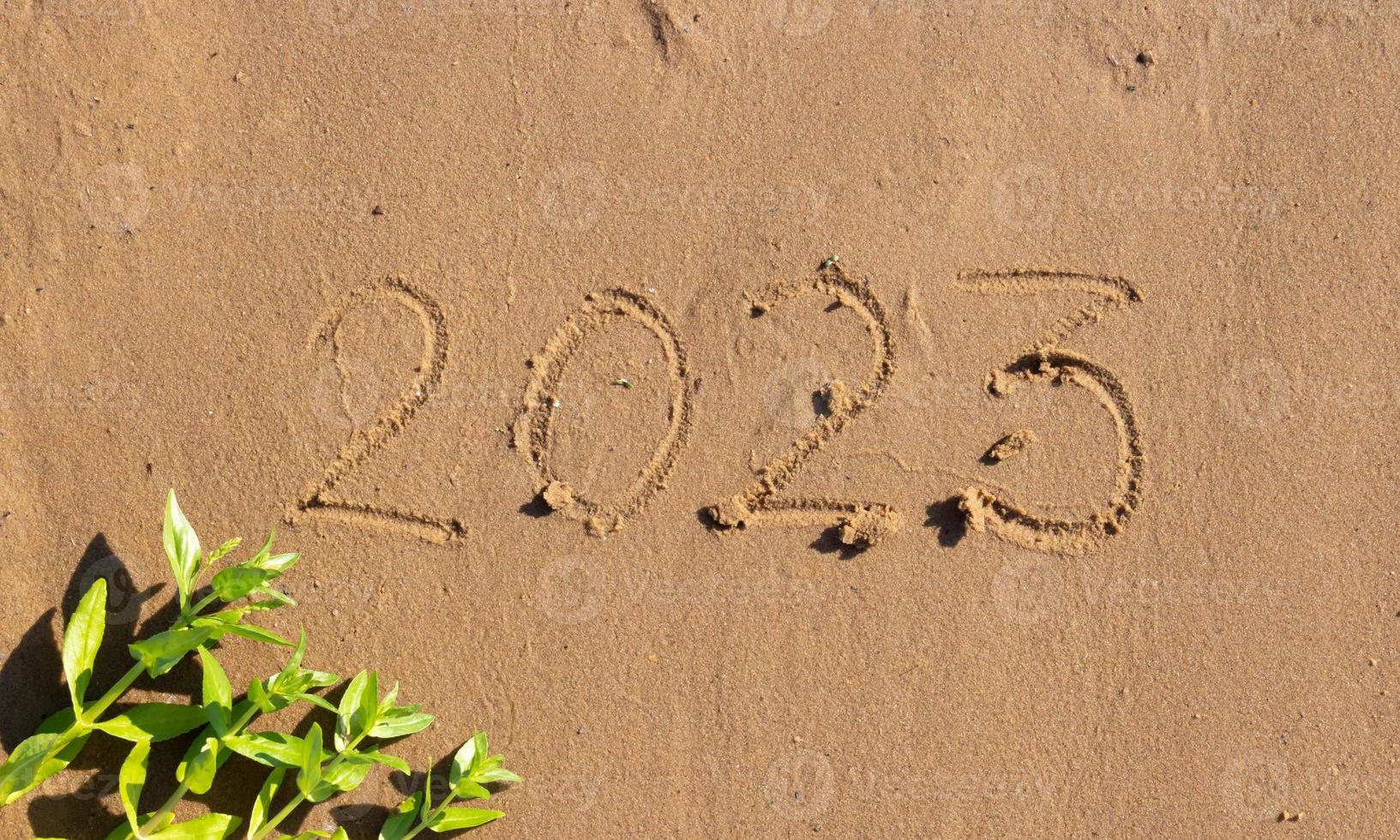 The numbers 2023 are written on the sand on the beach. The concept of the New Year. Happy New Year 2023 background. Travel during the Christmas holidays. photo