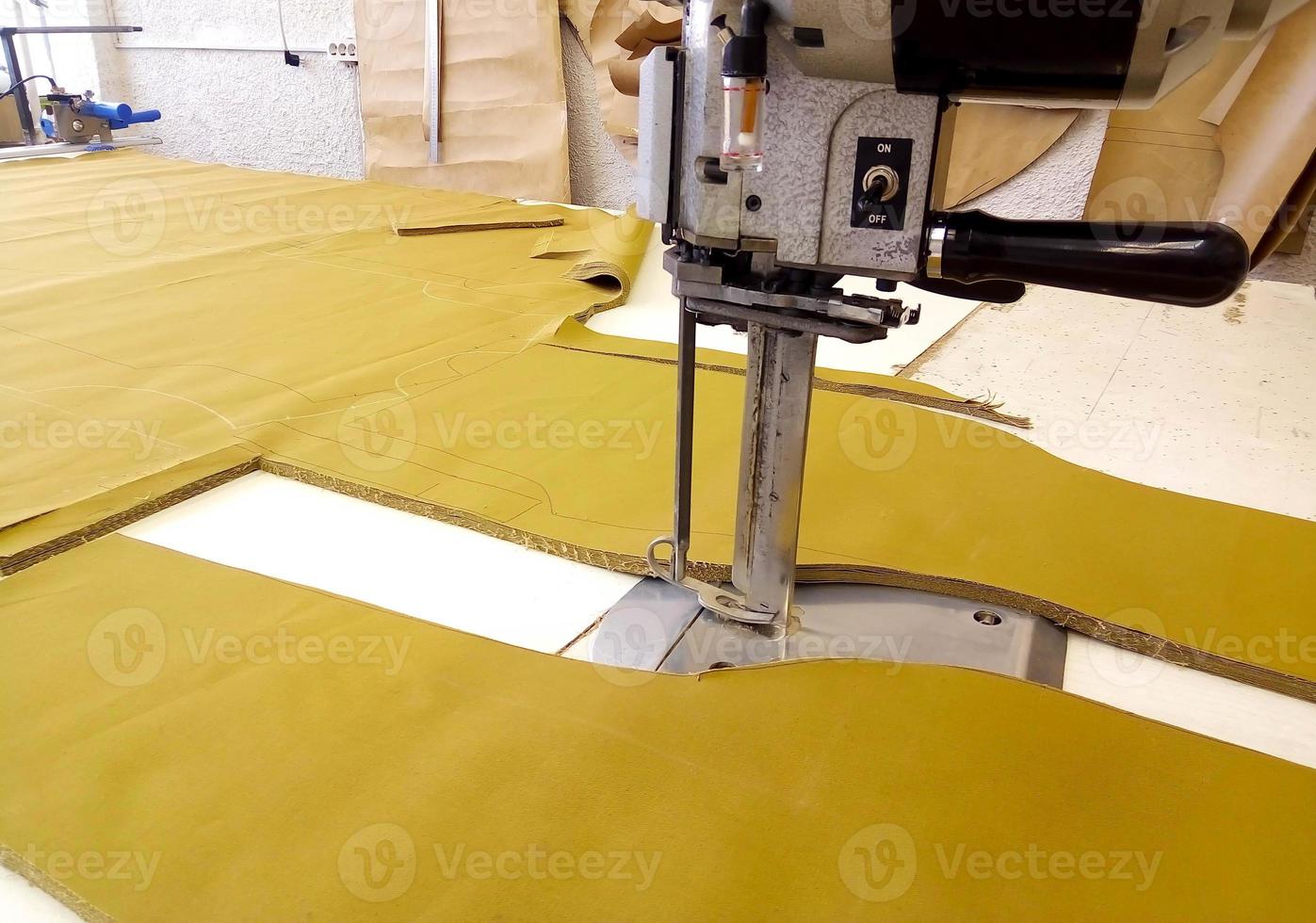 Tool cutter in the garment industry. Cutting parts of clothing with an electric knife made of multi-layer fabric photo
