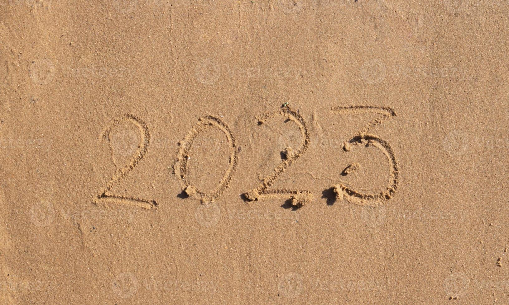 The numbers 2023 are written on the sand on the beach. The concept of the New Year. Happy New Year 2023 background. Travel during the Christmas holidays. photo