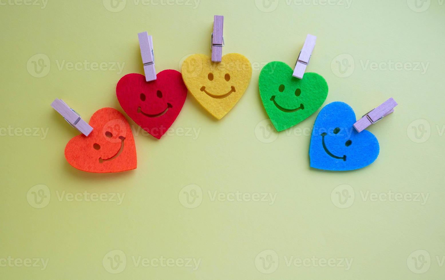 A flower made of felt multicolored hearts. Valentine's day background with beautiful toy hearts isolated on yellow background. . Bright hearts with smiles on a yellow background. Copy space photo