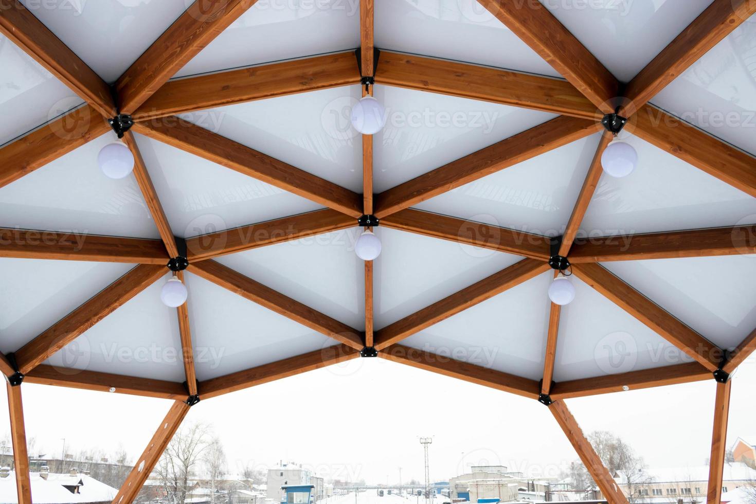 Glass ceiling with lanterns in a brown wooden gazebo outdoors in winter photo