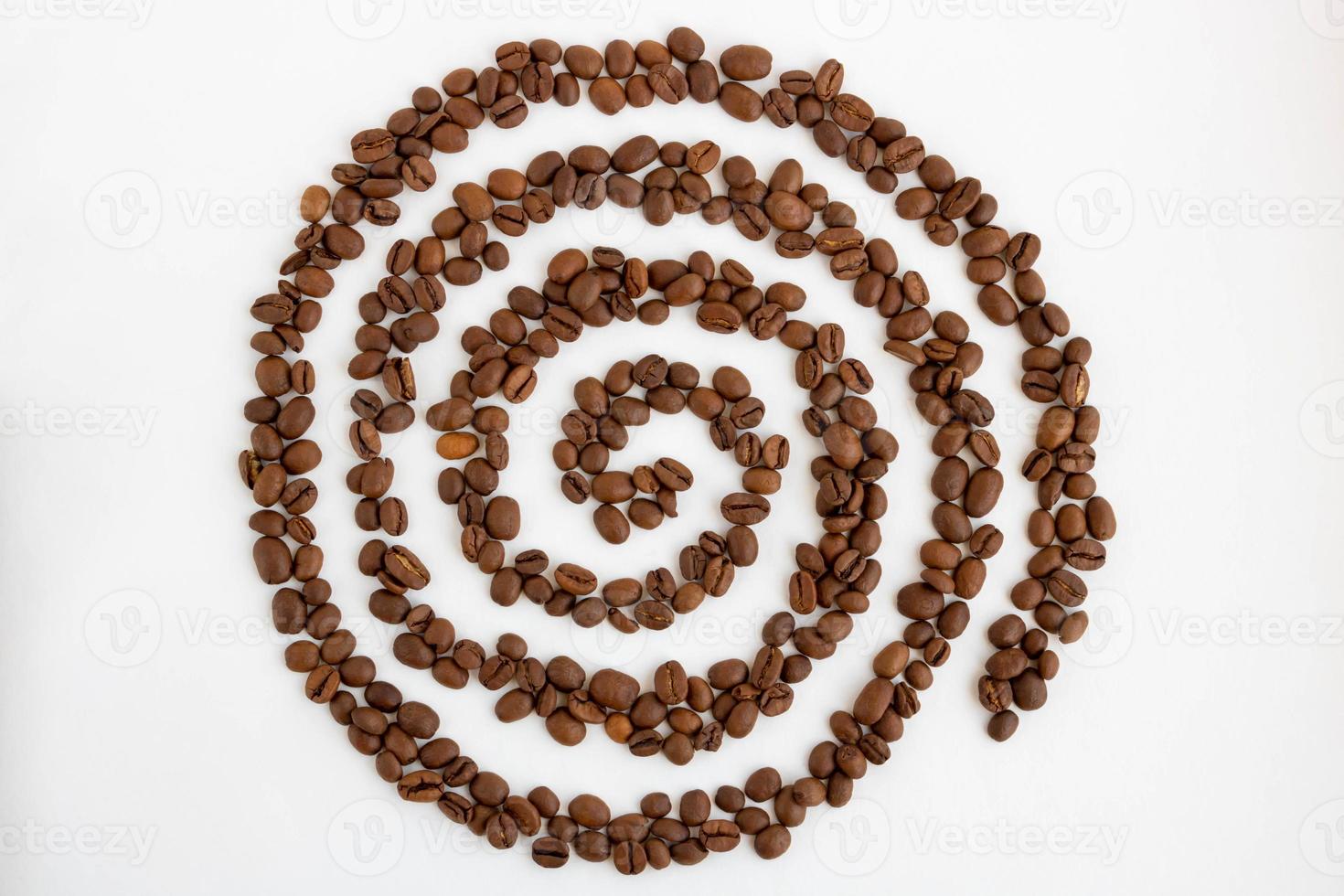 Coffee beans are laid out on a white background in the form of a spiral photo