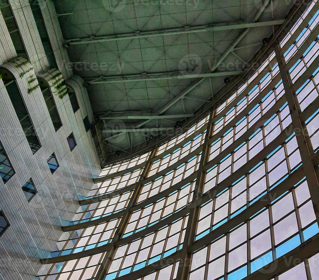The inside of a tall building, lots of glass and very futuristic. photo