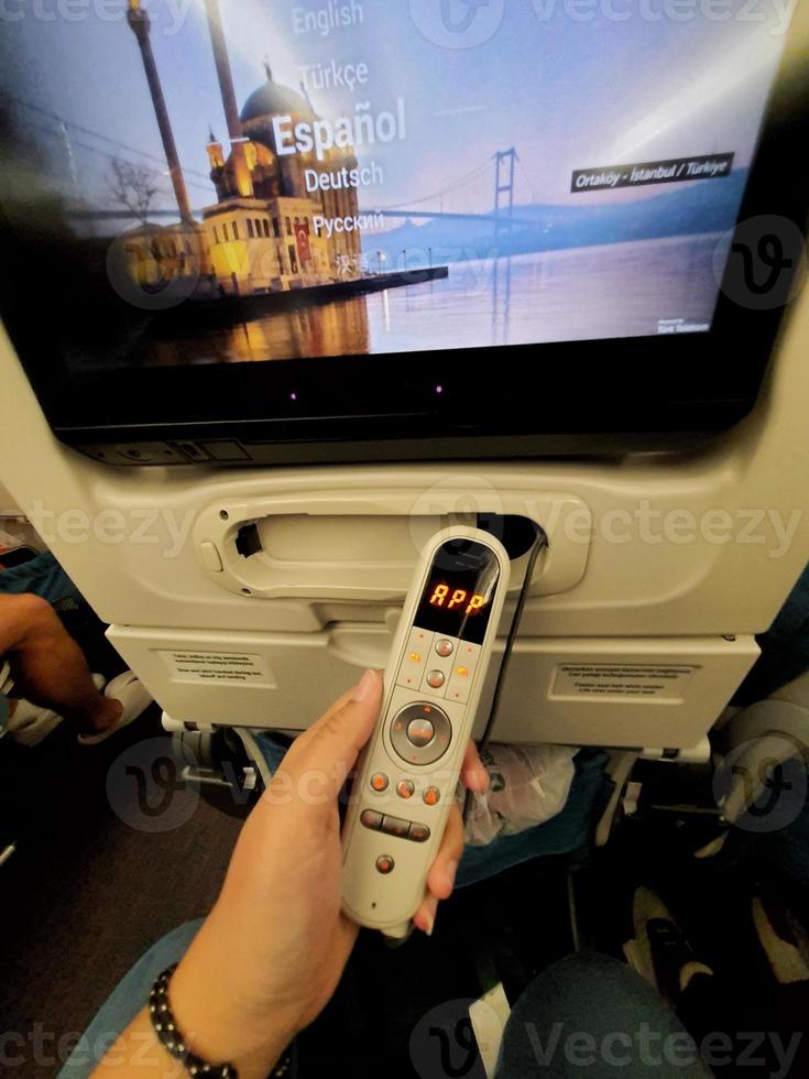 The interior of the passenger seat of a Turkish Airlines plane that has a touch screen for in-flight entertainment. Which is also equipped with a remote controller that also functions as a game stick photo