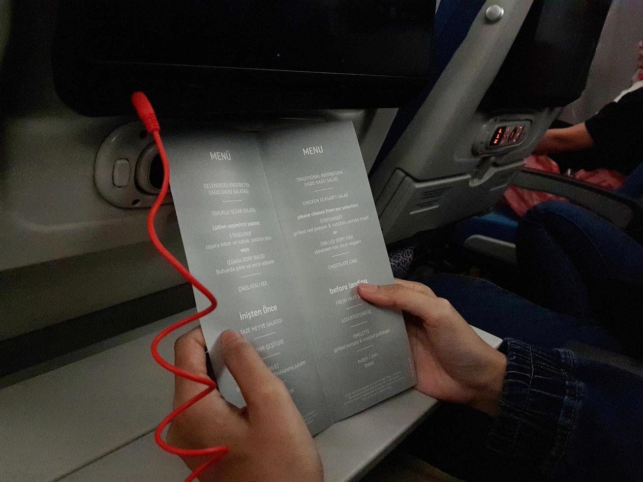 Turkey in July 2022. Two hands are holding a flight meal menu from Turkish Airline. photo