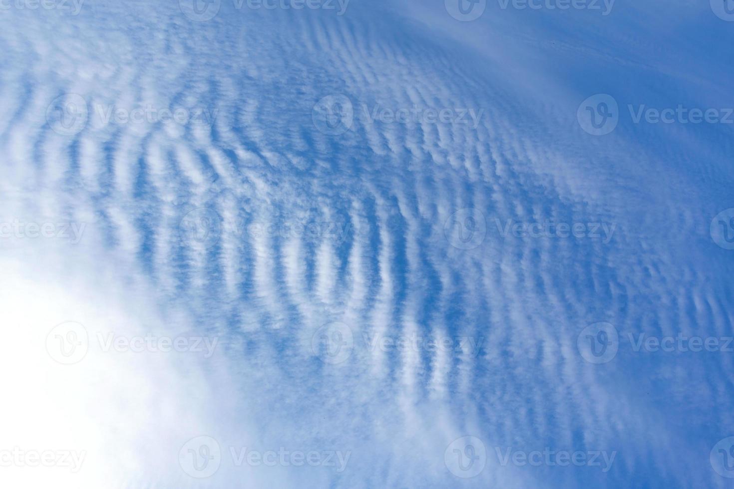 White clouds like a sea wave shape in the light blue sky as background. photo