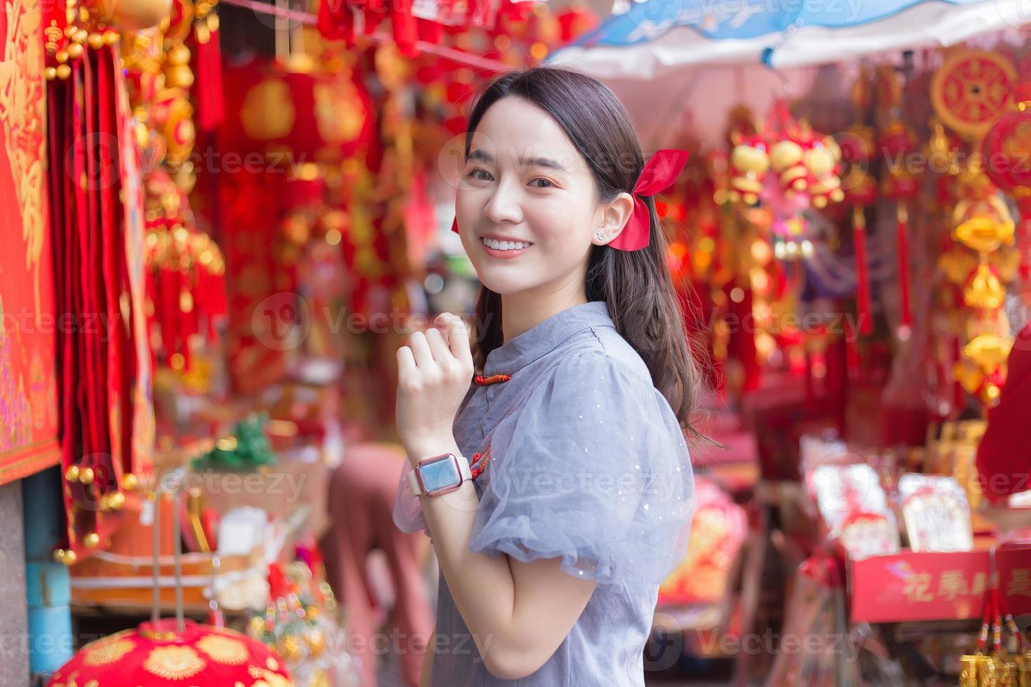 Asian beautiful woman in long hair wears grey dress stands among Chinese new year theme. photo