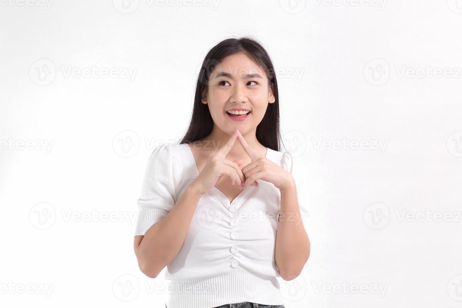 Asian beauty lady standing smiling in pink dress is looking at something while touching her face on a white background. photo