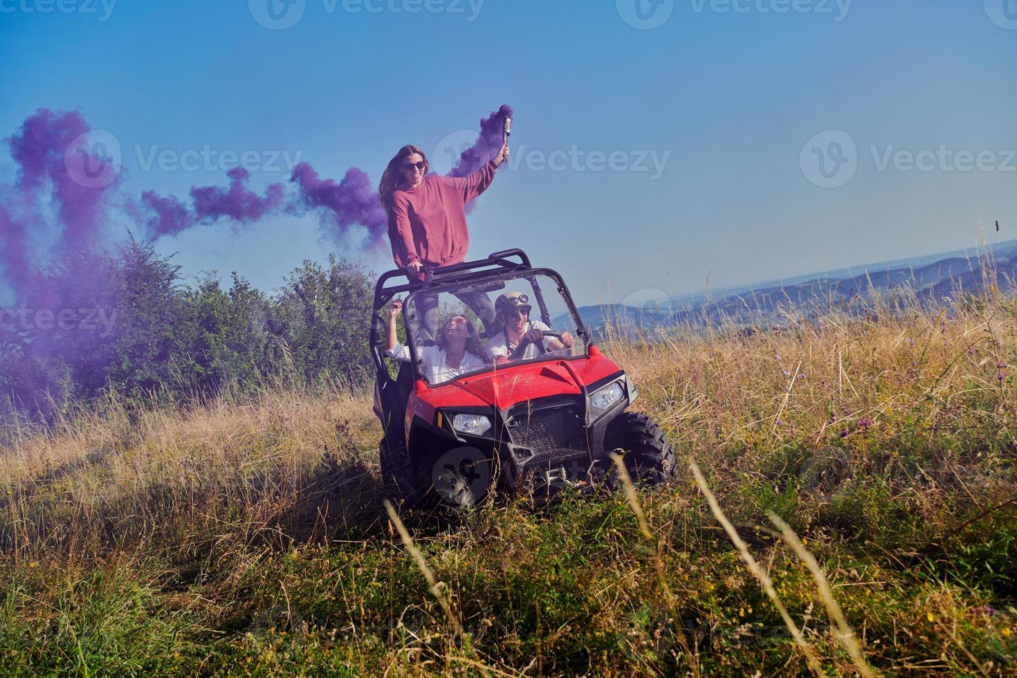 excited people having fun enjoying beautiful sunny day holding colorful torches while driving a off road buggy car photo