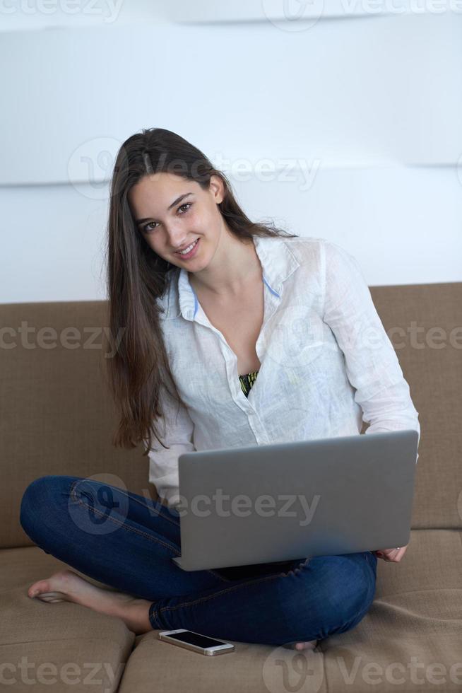 relaxed young woman at home working on laptop computer photo