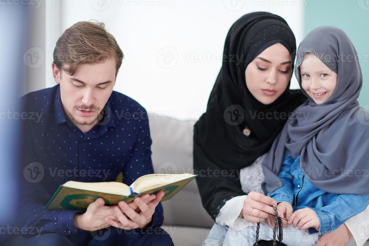 familia musulmana leyendo el corán y rezando en casa foto
