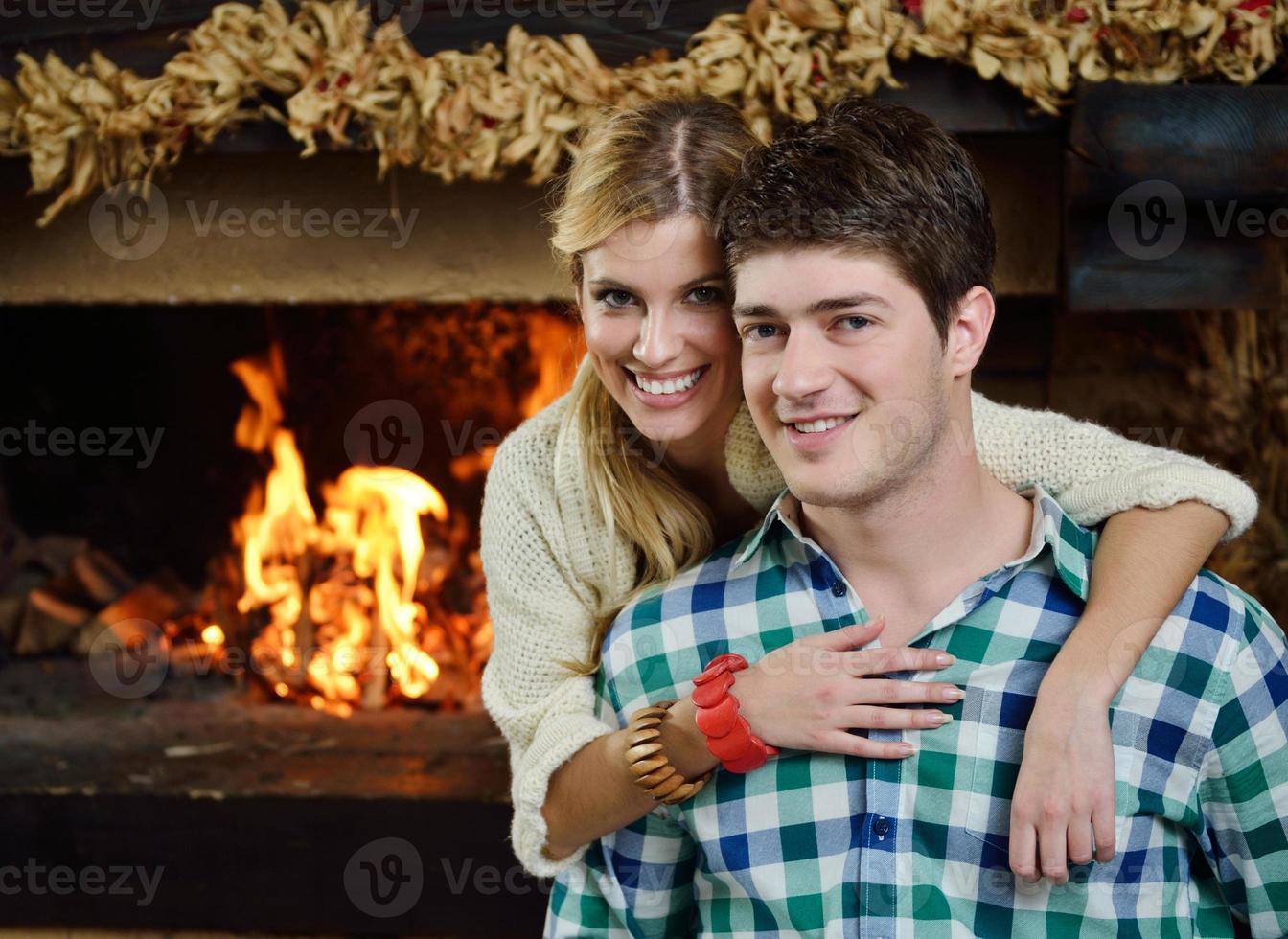 Young romantic couple sitting on sofa in front of fireplace at home photo