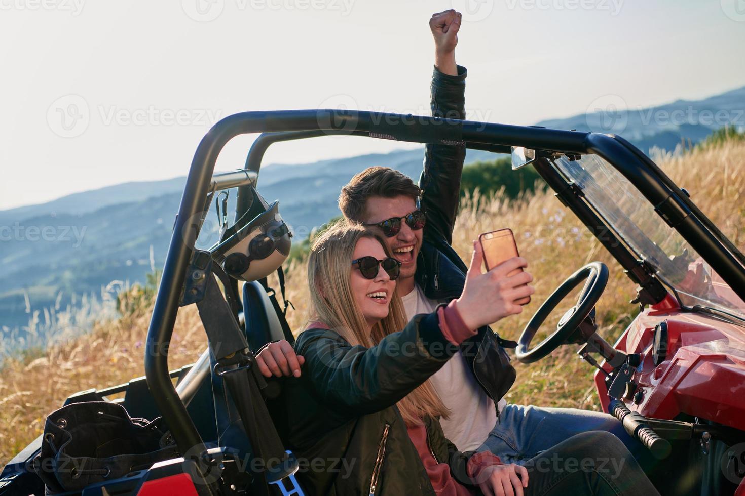 couple enjoying beautiful sunny day taking selfie picture while driving a off road buggy photo