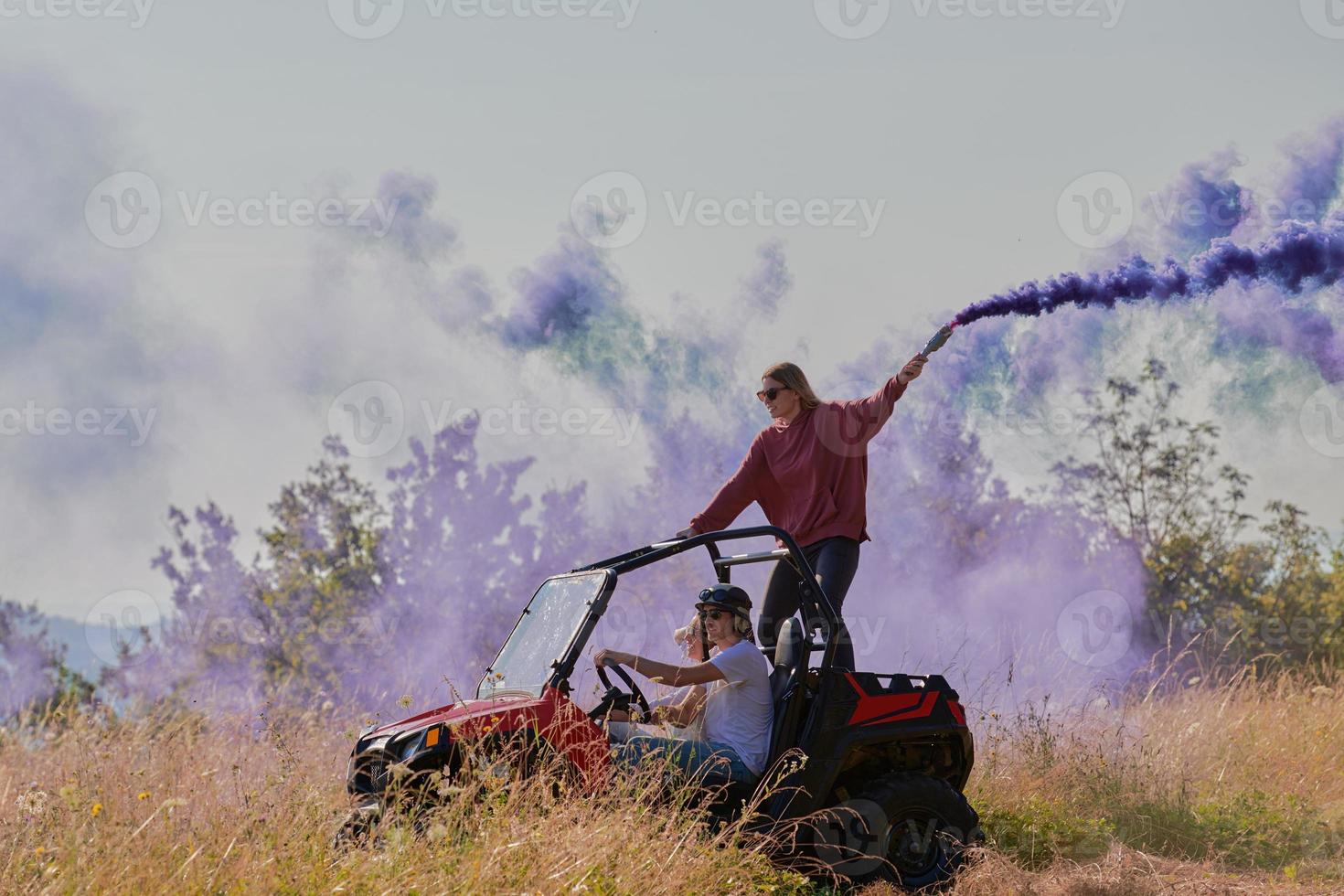 excited people having fun enjoying beautiful sunny day holding colorful torches while driving a off road buggy car photo