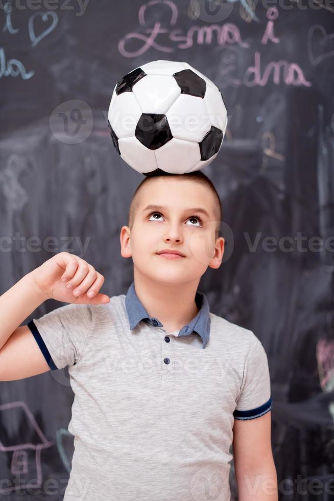 happy boy holding a soccer ball on his head photo