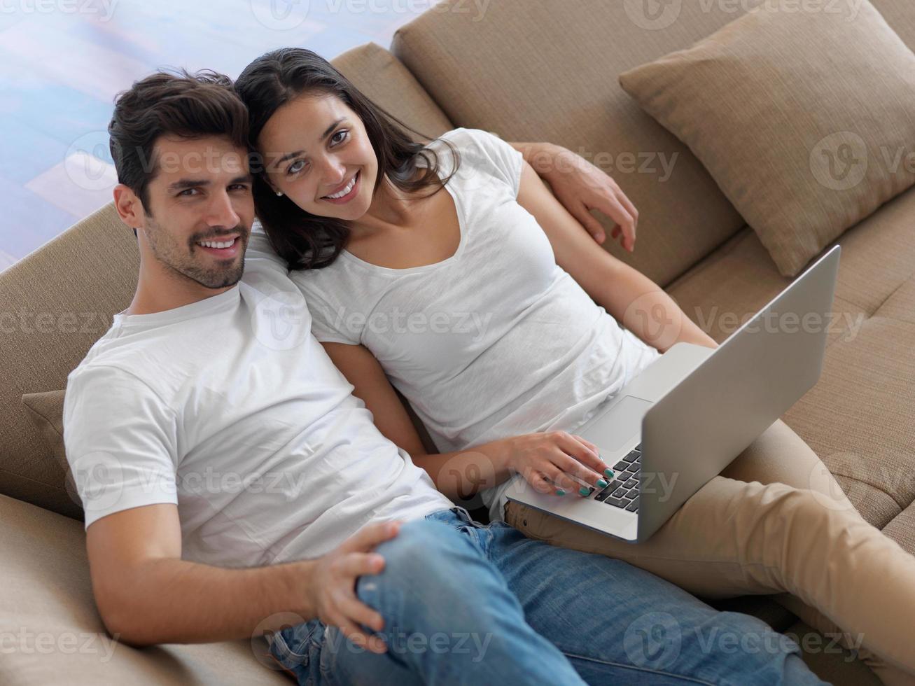 relaxed young couple working on laptop computer at home photo