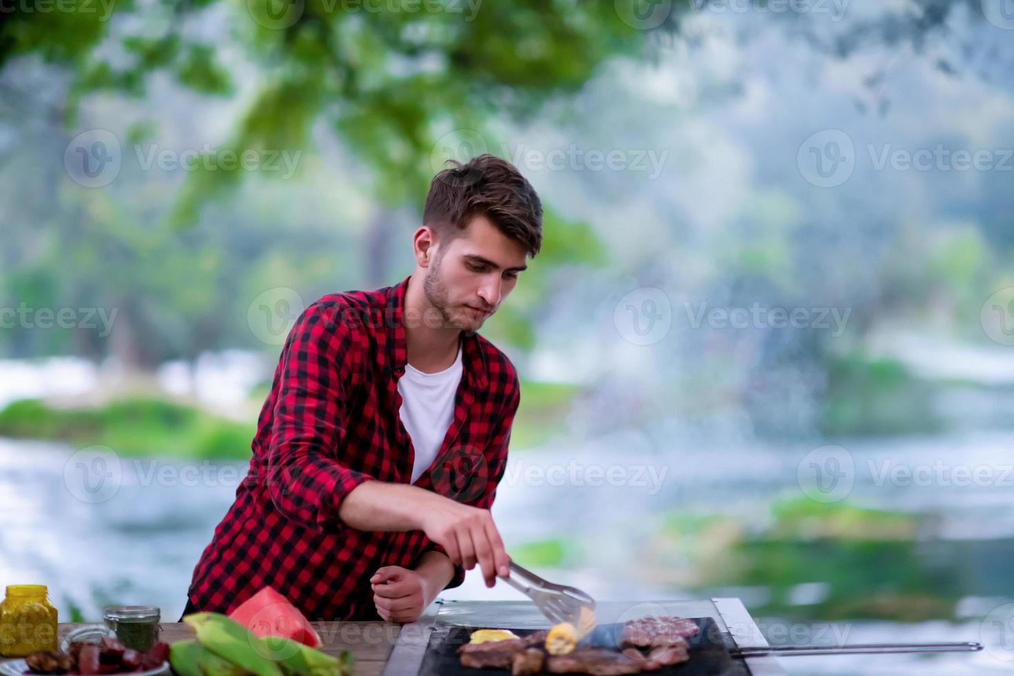 hombre cocinando comida sabrosa en la parrilla de la barbacoa foto