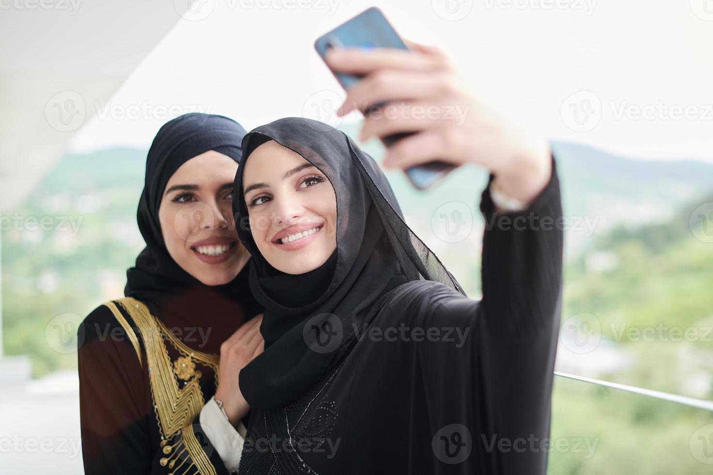mujeres musulmanas tomándose una foto selfie en el balcón