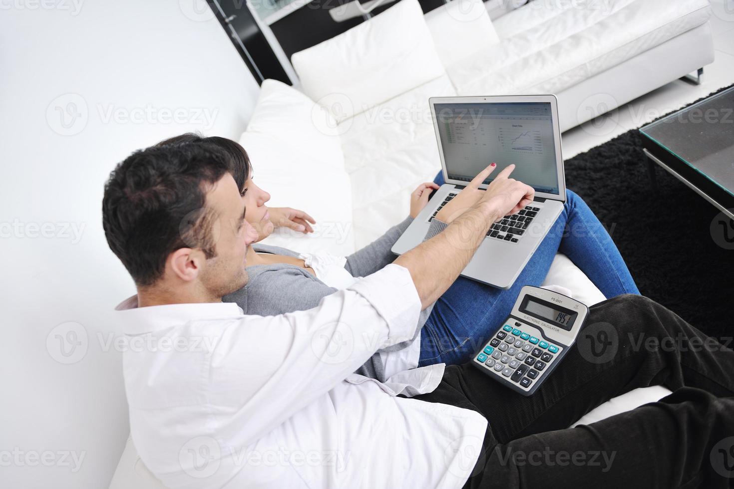 una pareja alegre se relaja y trabaja en una computadora portátil en una casa moderna foto