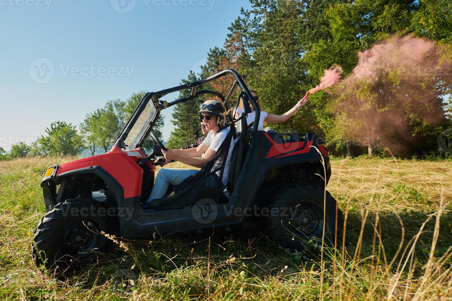 excited people having fun enjoying beautiful sunny day holding colorful torches while driving a off road buggy car photo