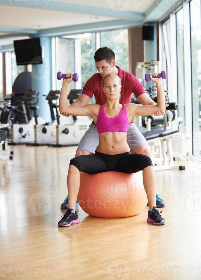 joven mujer deportiva con entrenador ejercicio levantamiento de pesas foto