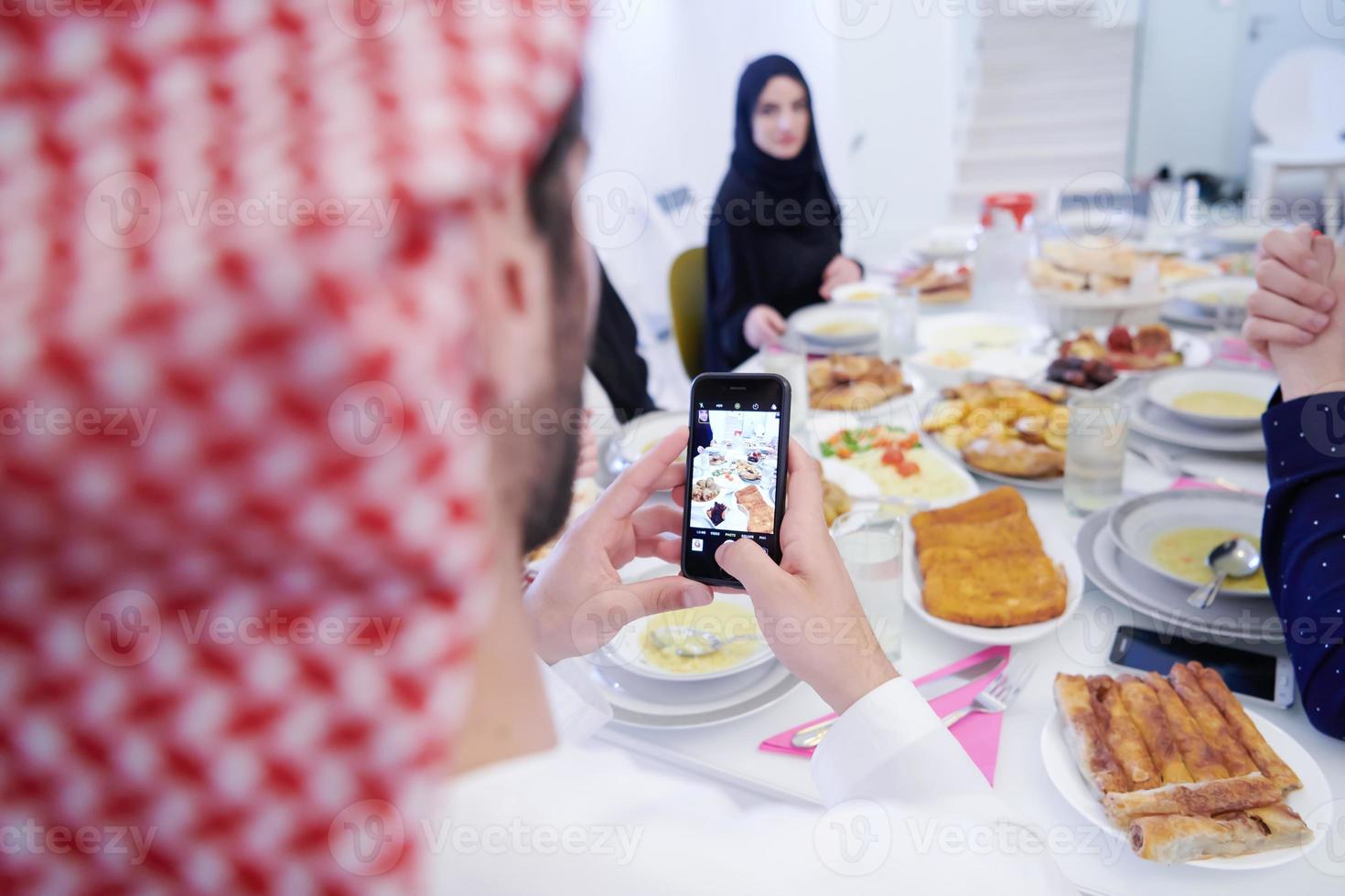 Muslim family having Iftar dinner taking pictures with mobile phone photo