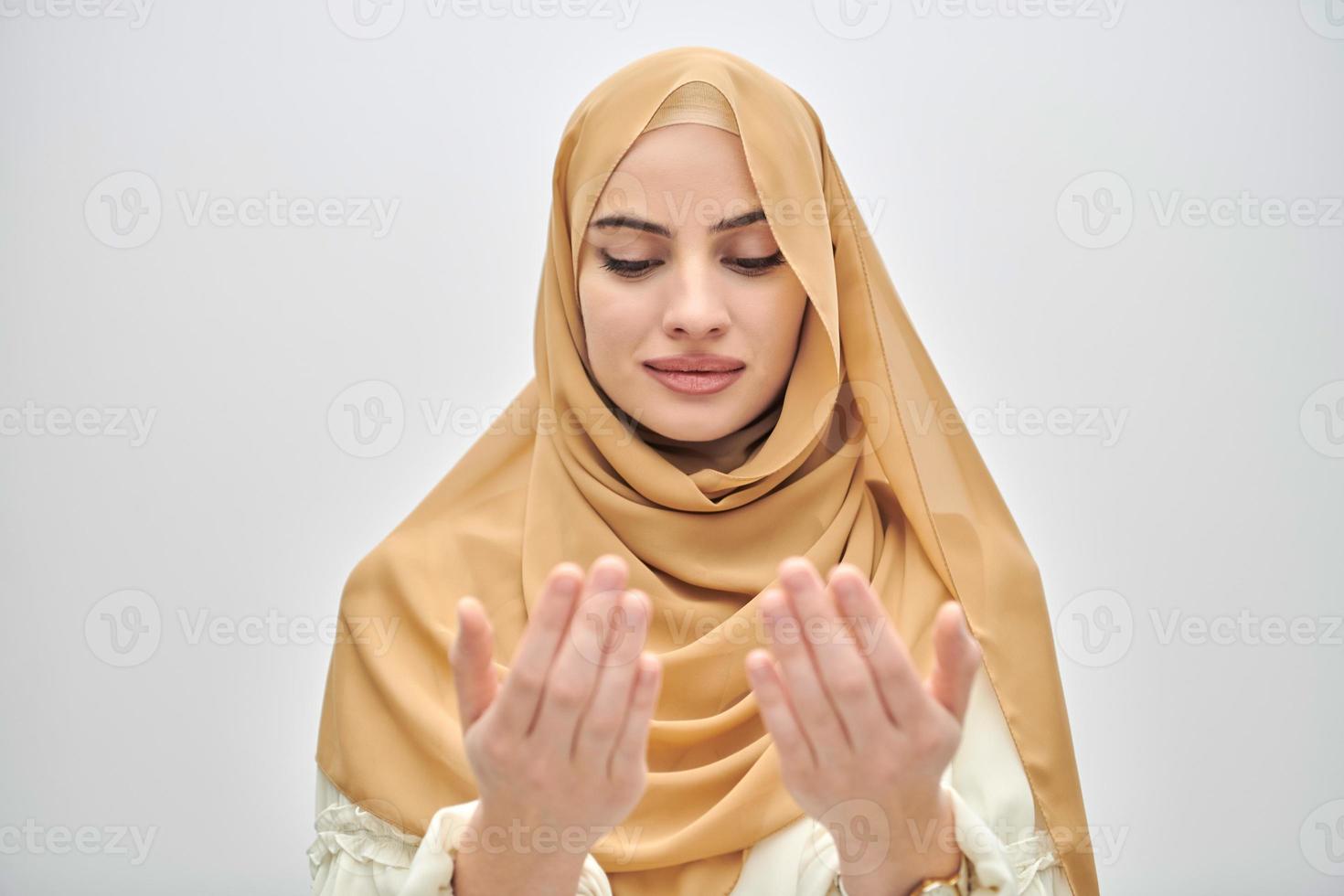 Portrait of young muslim woman making dua, praying to God photo