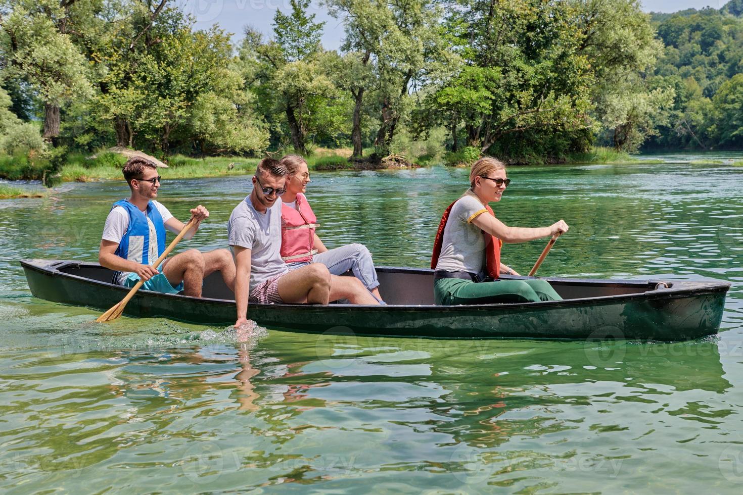 Group adventurous explorer friends are canoeing in a wild river photo