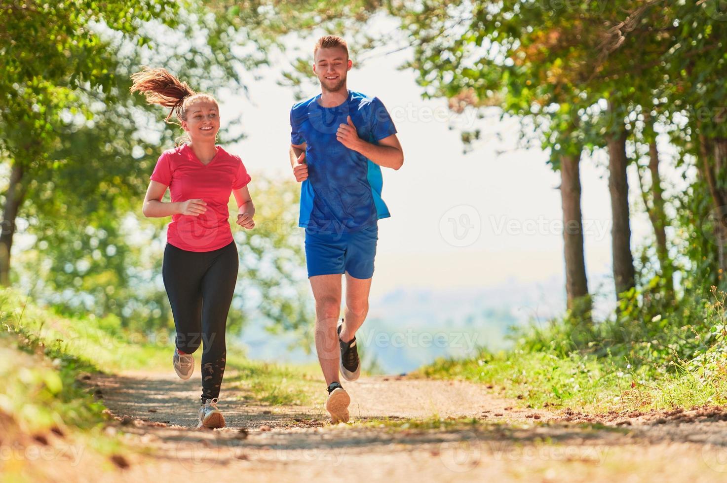 couple enjoying in a healthy lifestyle while jogging on a country road photo