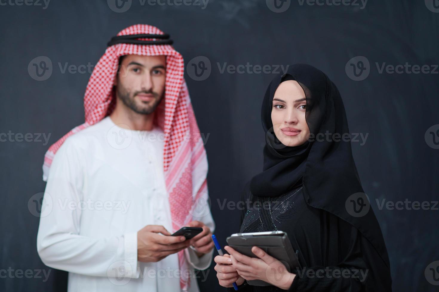 muslim couple using modern technology in front of black chalkboard photo