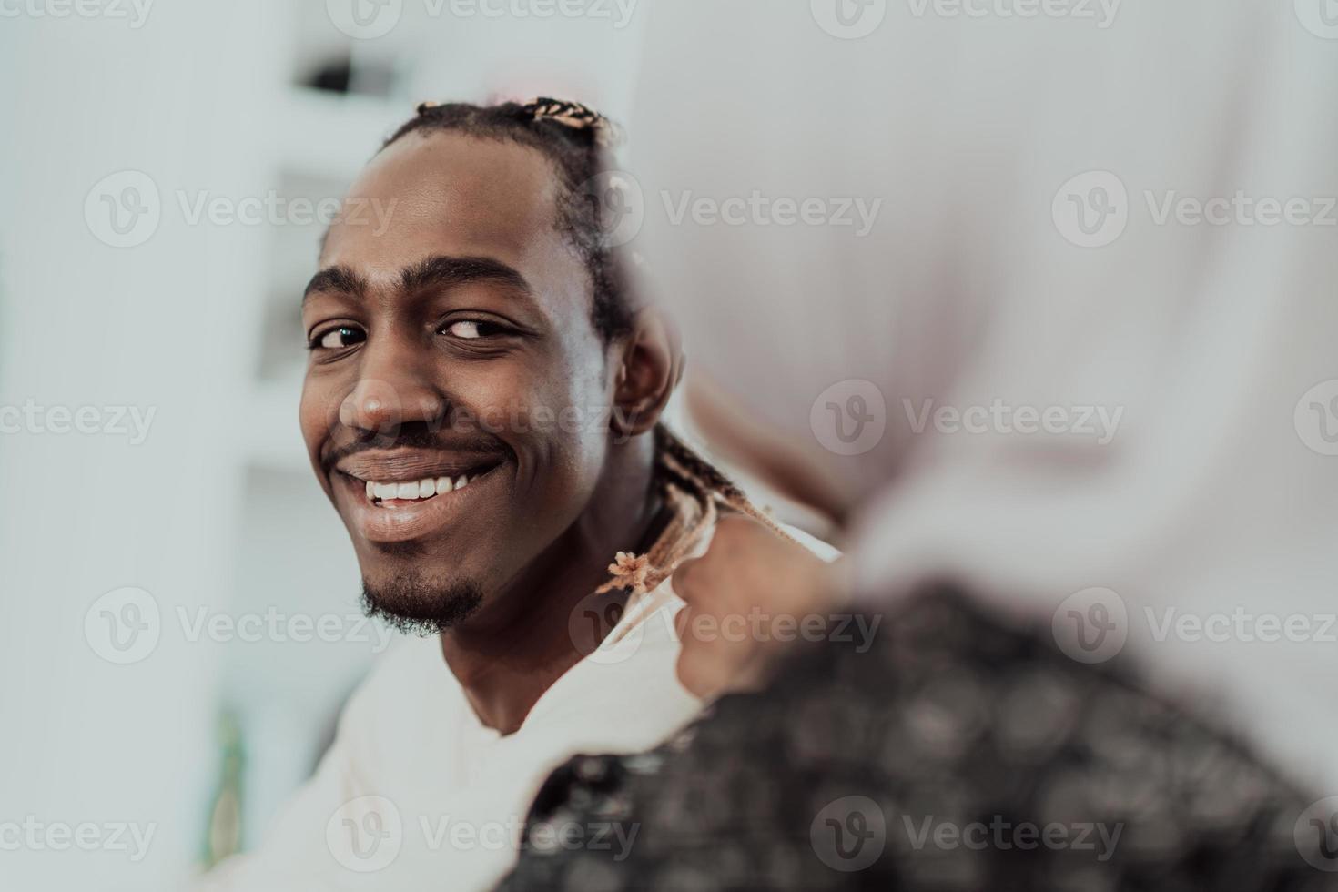 A young Muslim couple has a romantic time at home while the woman makes the hairstyle for her husband female wearing traditional Sudan Islamic hijab clothes. photo