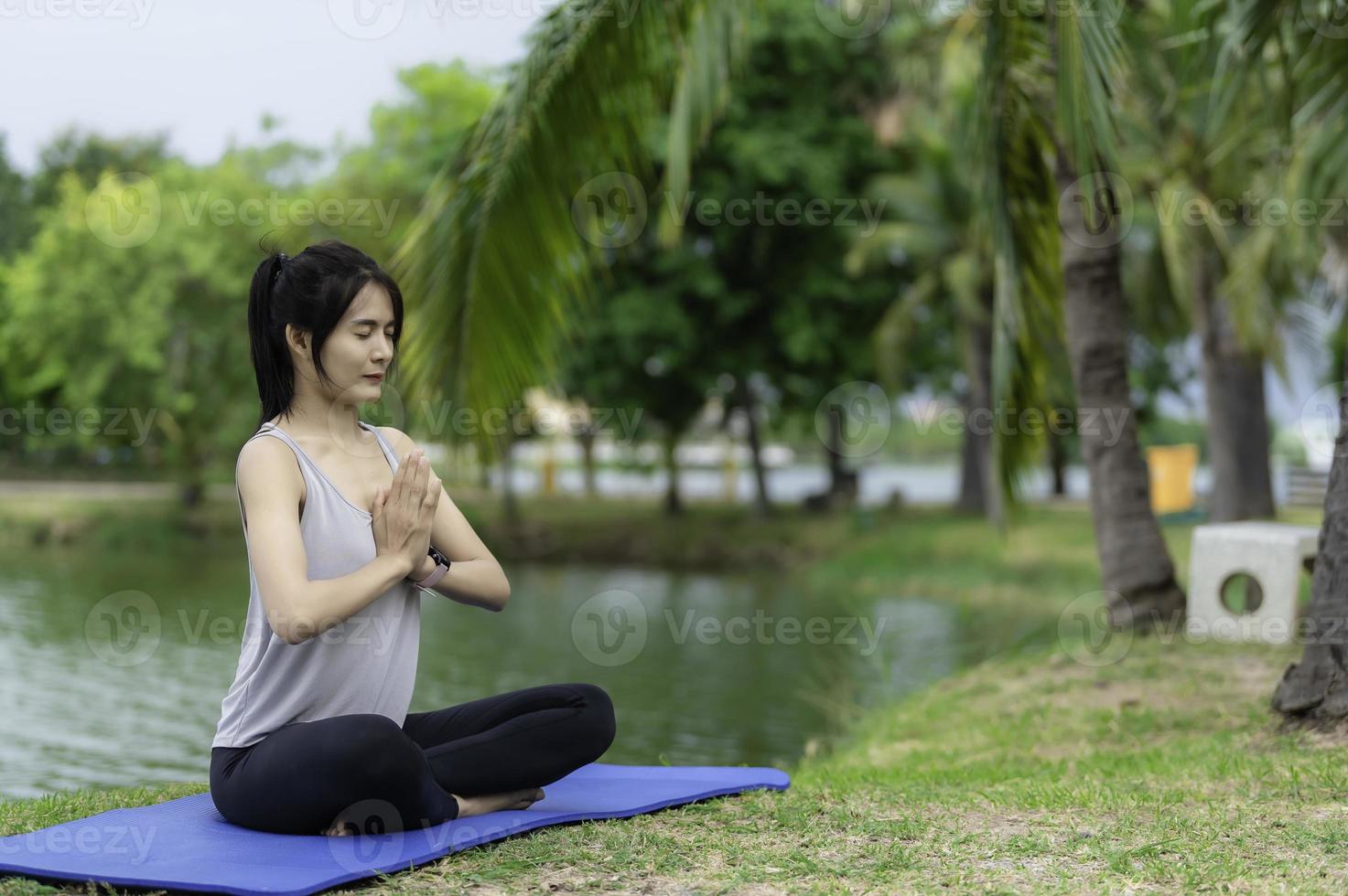 retrato de una joven asiática que juega yoga en el parque público foto