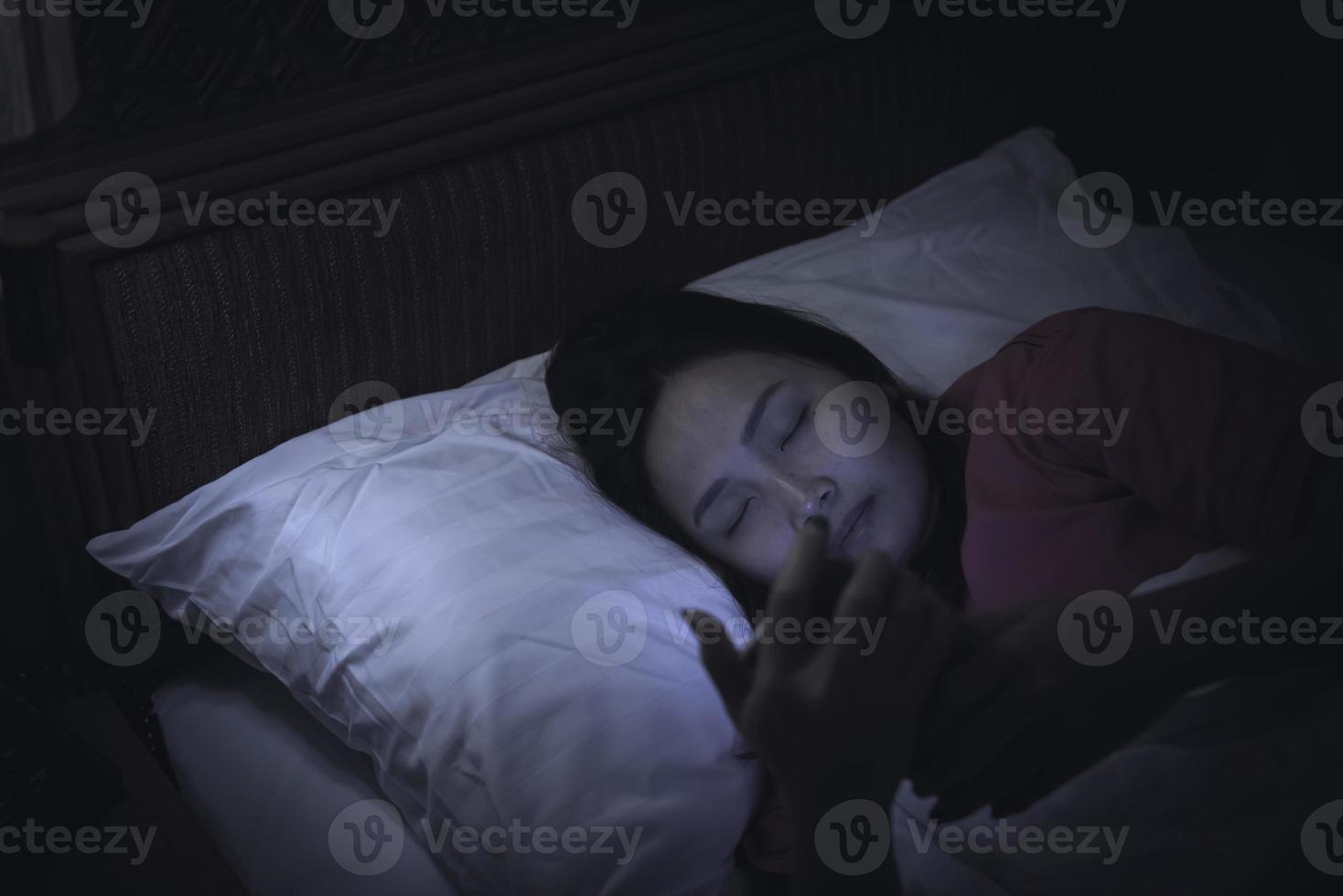 mujer asiática jugando en el teléfono inteligente en la cama por la noche, gente de Tailandia, adicto a las redes sociales foto