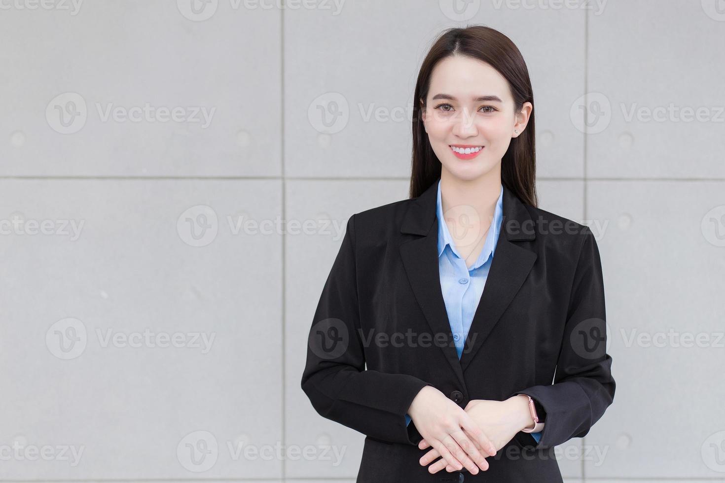 mujer trabajadora de negocios asiáticos se pone de pie y sonríe felizmente en el lugar de trabajo. foto