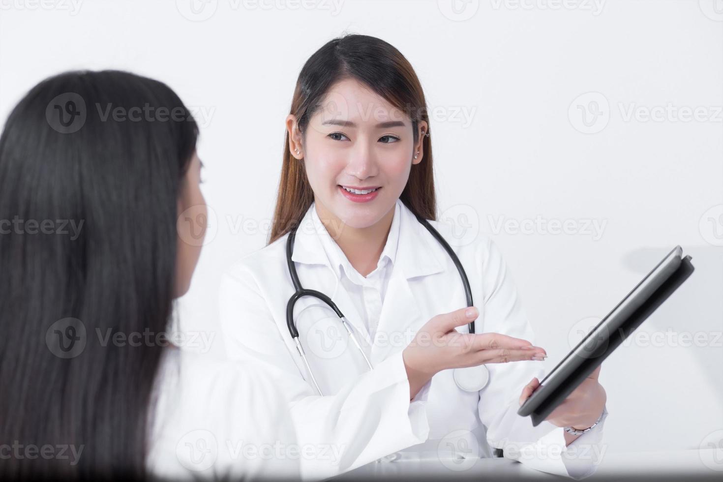 An Asian female doctor is talking to a female patient about his pain and symptoms in the hospital. photo